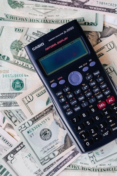 Calculator placed over stack of USA dollars