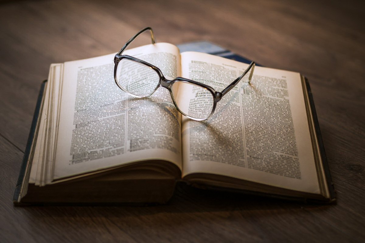 book on table with reading glasses