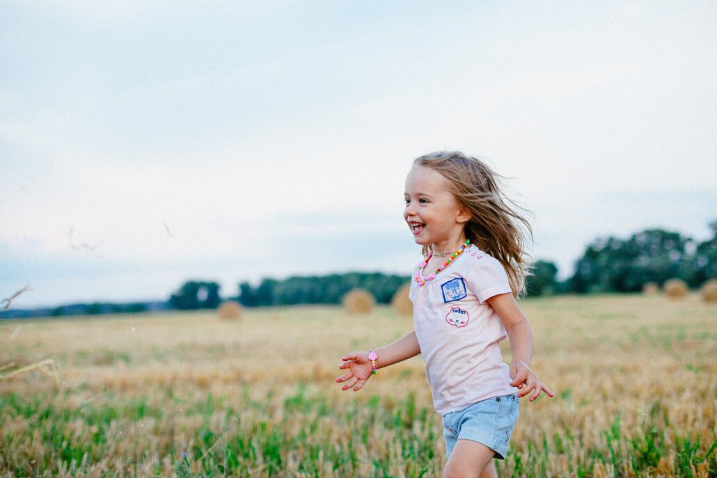 child laughing and running in field