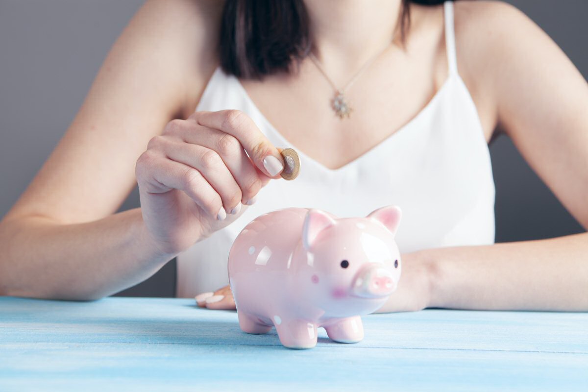 woman dropping money in piggy bank