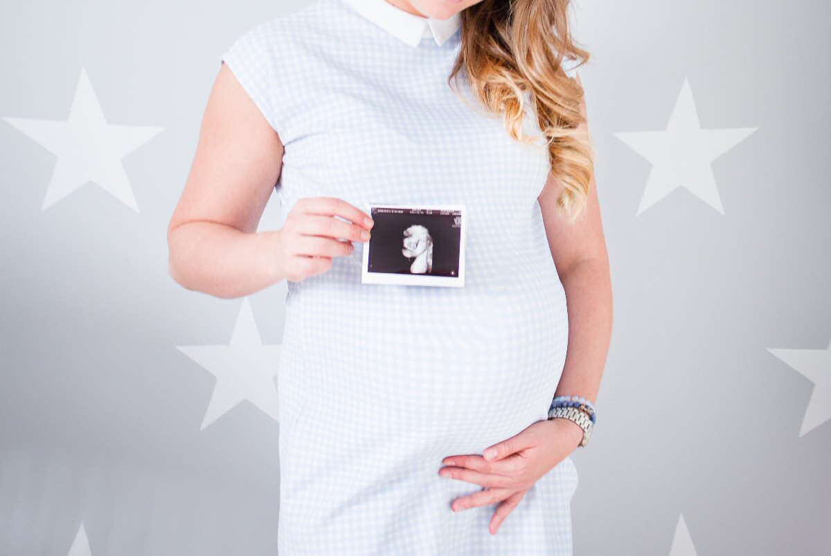 pregnant woman holding ultrasound photo of unborn child